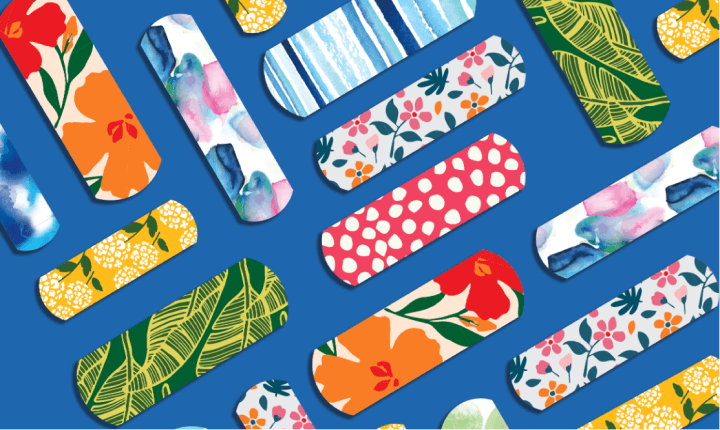 Assortment of BAND-AID® Brand limited-edition collection of cute & fun bandages laid out on a blue background