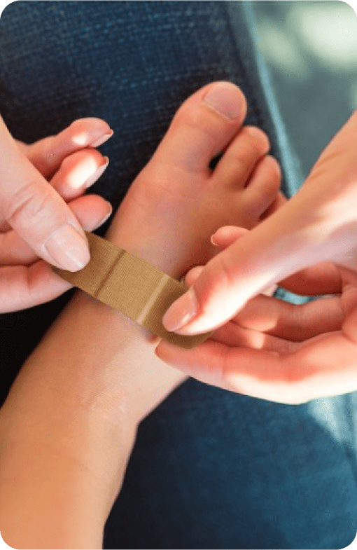 Adult placing a Band-Aid adhesive bandage on a child’s foot.