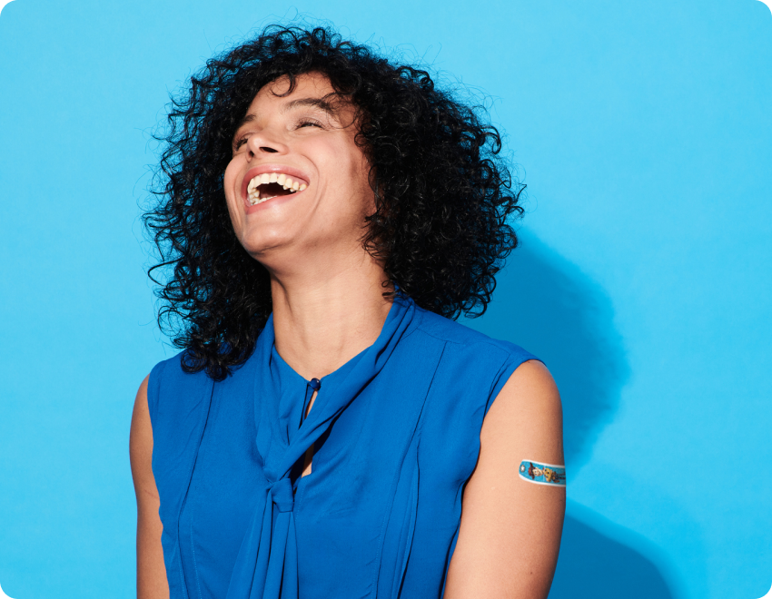 Woman laughing with BAND-AID® Brand product on left arm