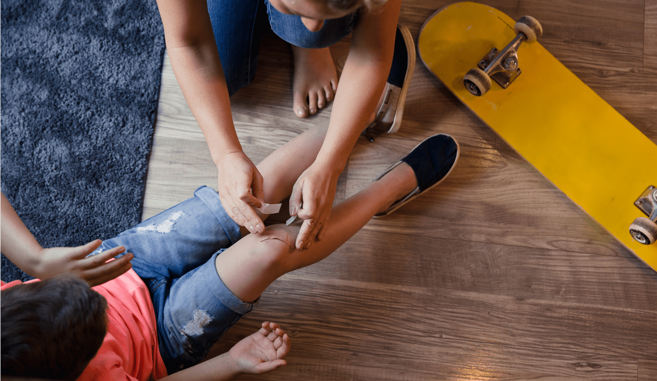 Person placing a bandage on a scrape on young child’s knee