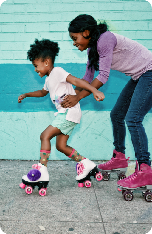 Woman teaching a young girl how to roller blade.
